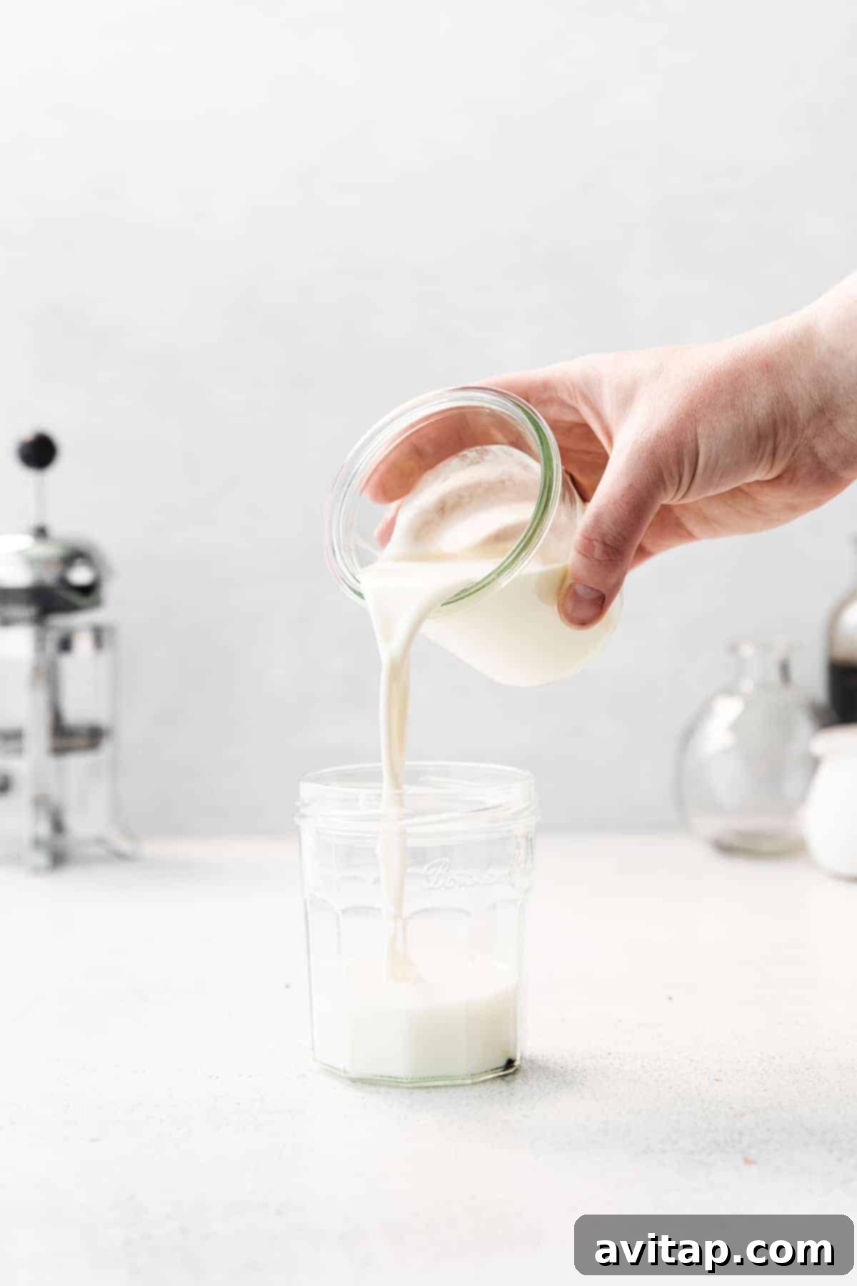 Pouring prepared vanilla sweet cream into a jar, ready for storage or frothing.