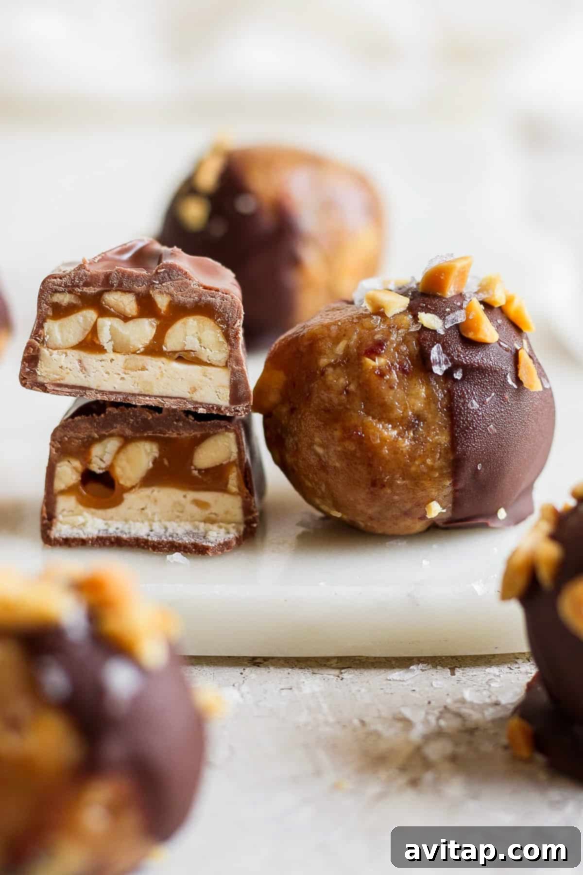 No Bake Snickers Fuel Bites 7 A charming close-up of a plate laden with chocolate-covered peanuts, hinting at the delightful toppings of the energy balls.