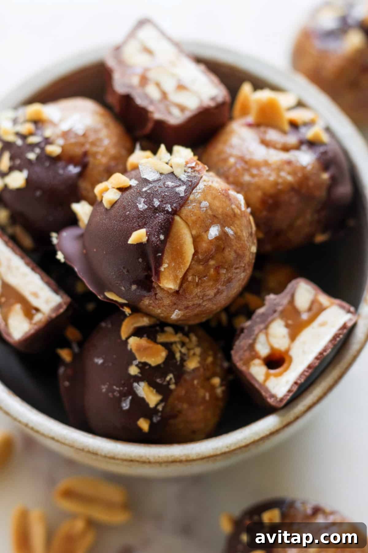 No Bake Snickers Fuel Bites 6 A bowl overflowing with chocolate peanut butter balls, showcasing their enticing texture and appearance.