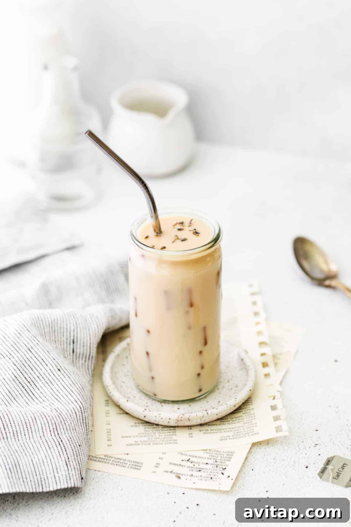 A refreshing Iced London Fog Latte in a clear glass, garnished with a sprig of lavender.