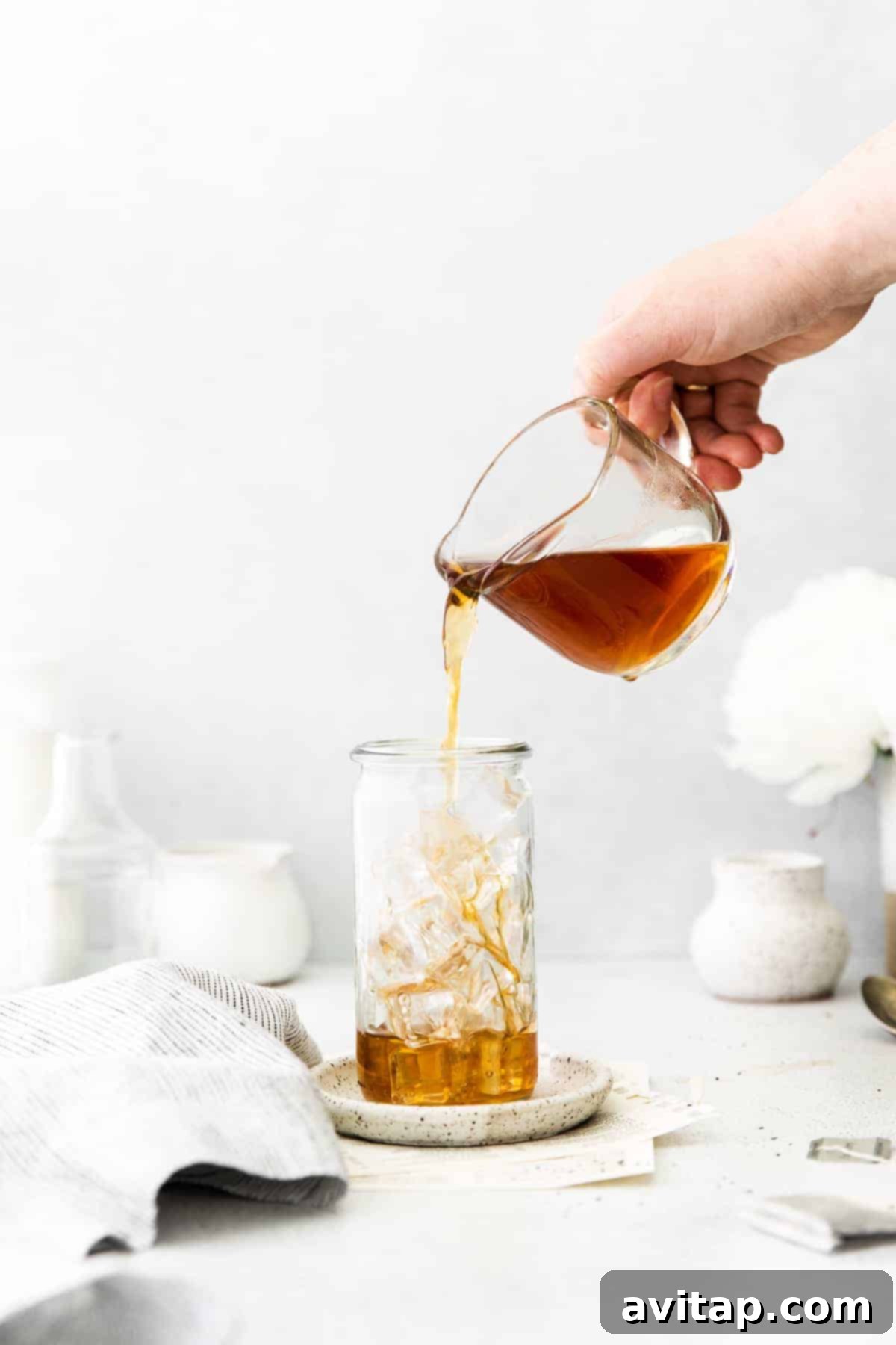 Someone pouring freshly brewed Earl Grey tea into a glass filled with ice.