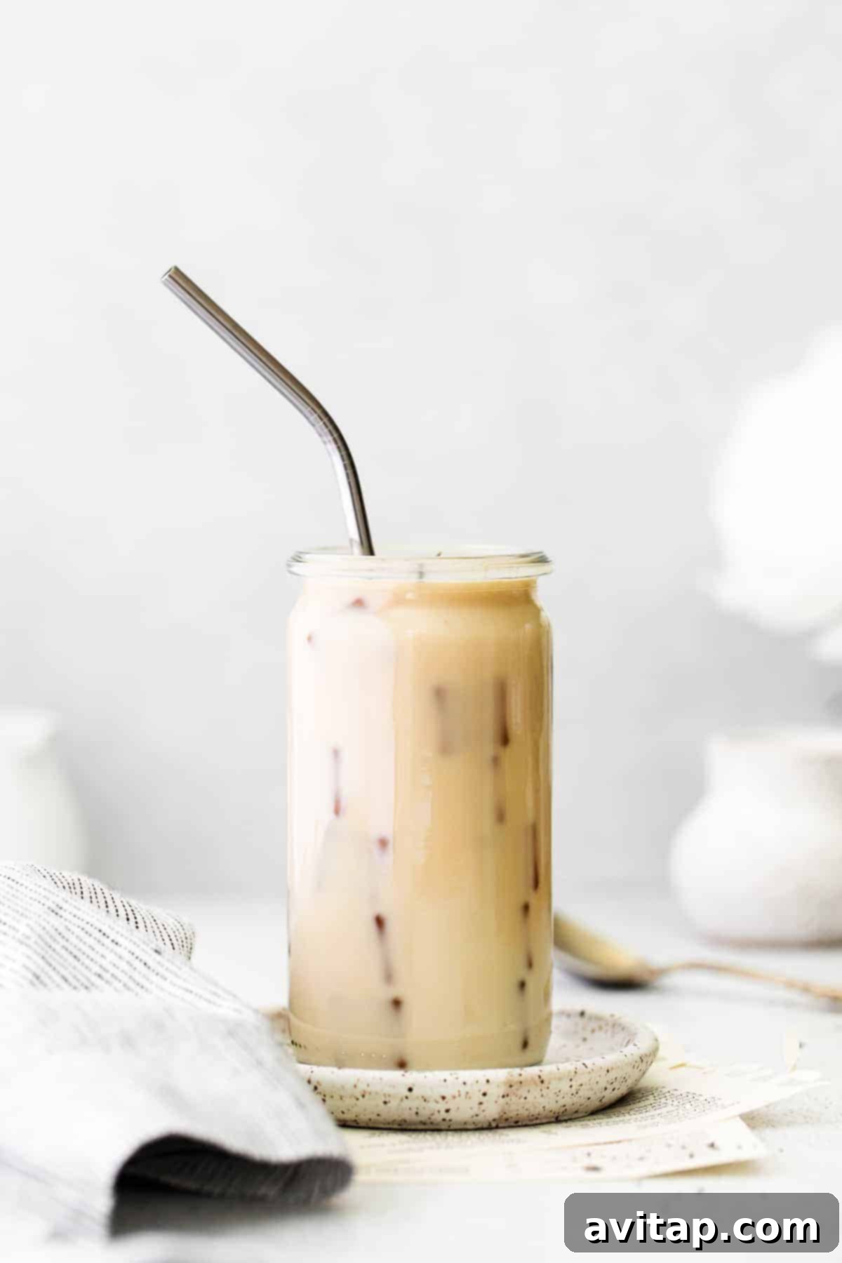 A beautifully presented Iced London Fog Latte in a glass with a straw, ready to drink.