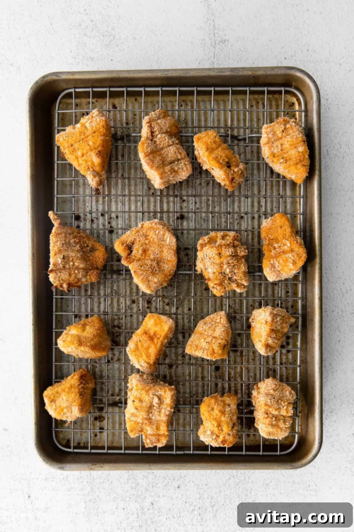 Beautifully golden brown and crispy baked chicken nuggets on a baking sheet, fresh from the oven.