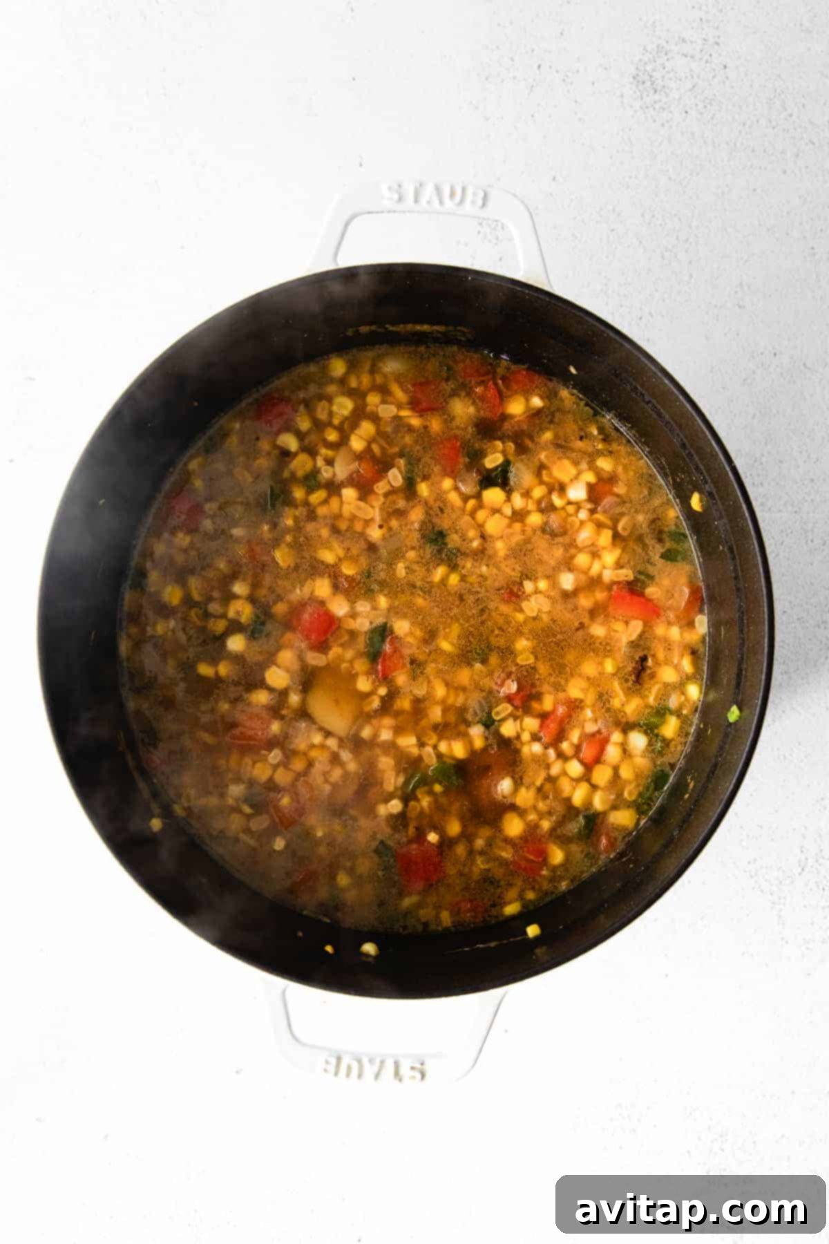 The simmering corn chowder in a Dutch oven, becoming thick and creamy after blending.