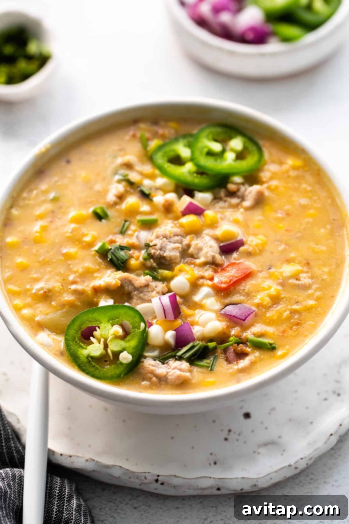 Corn chowder garnished with fresh chives, cilantro, and crispy ground pork.