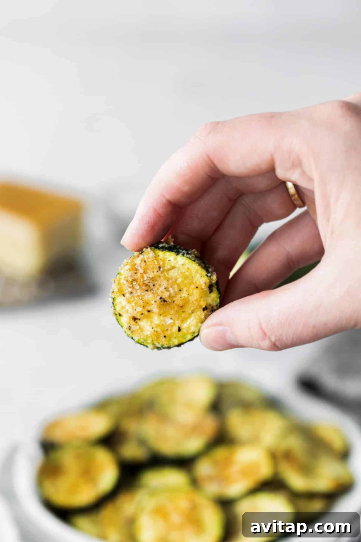 Enjoying a Slice of Crispy Air Fryer Zucchini A hand holding a single slice of crispy air fryer zucchini.