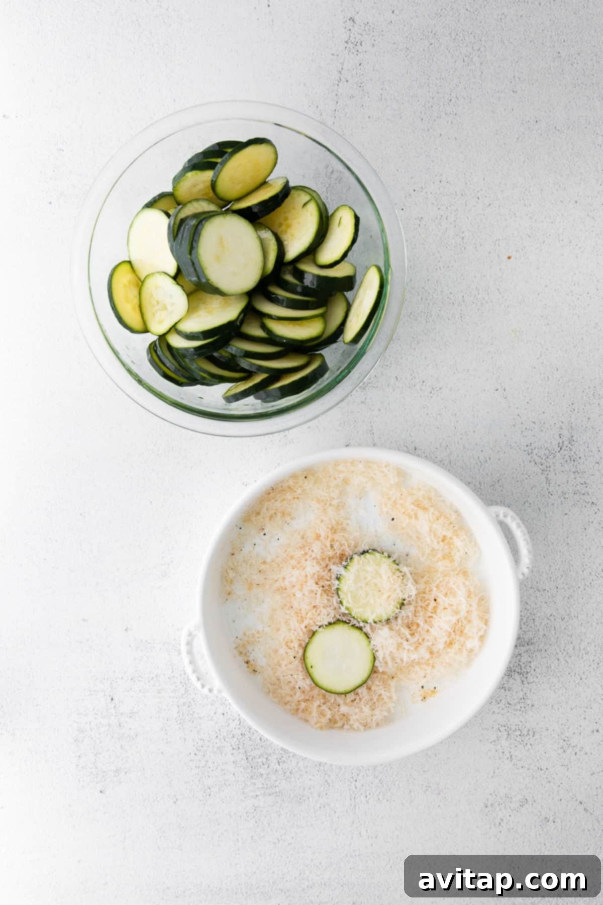 Sliced zucchini rounds being dredged through a parmesan and spice mixture before air frying.