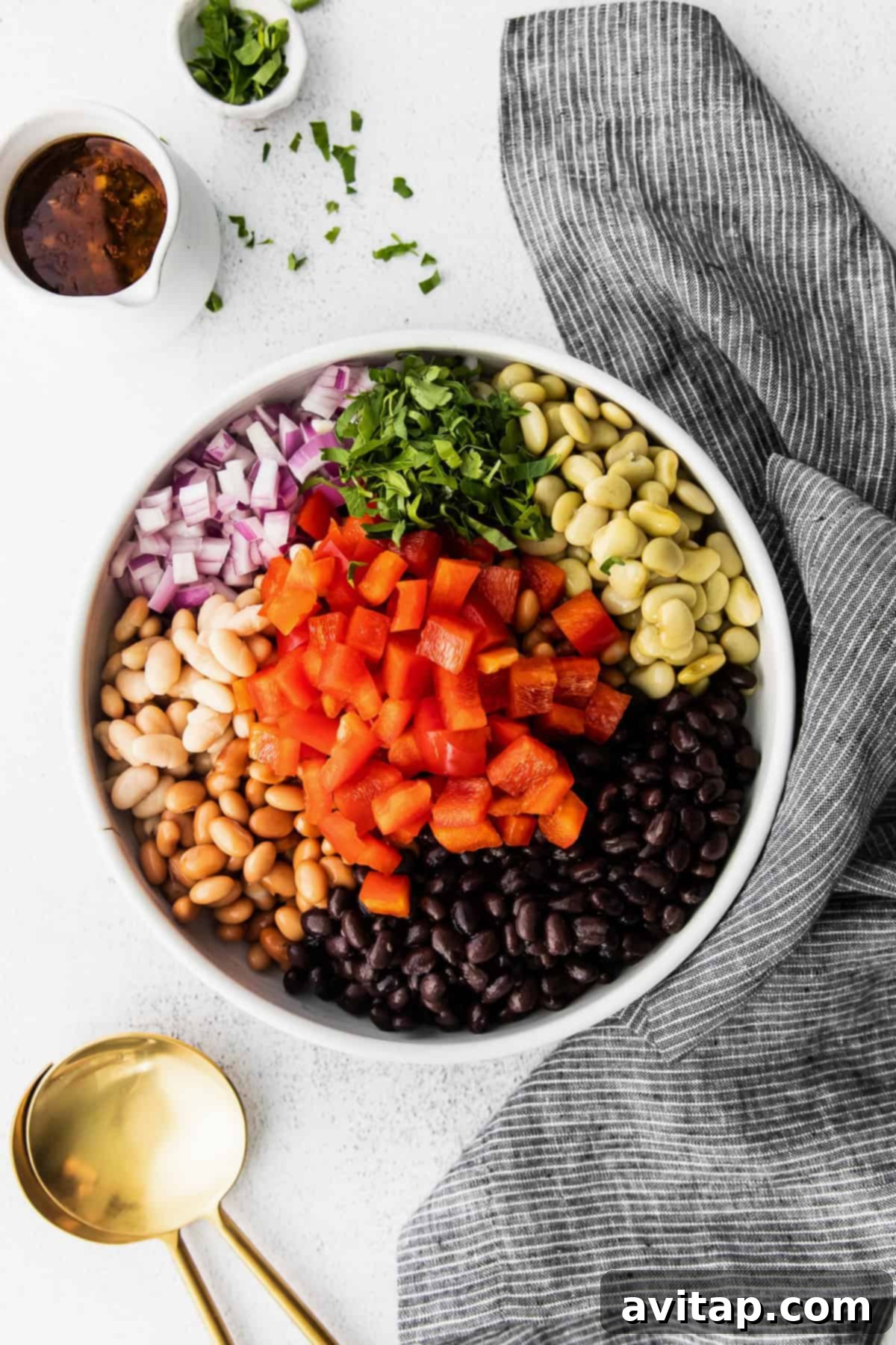 A large mixing bowl filled with all the colorful ingredients for a homemade bean salad, ready to be tossed with dressing for a fresh, healthy meal.