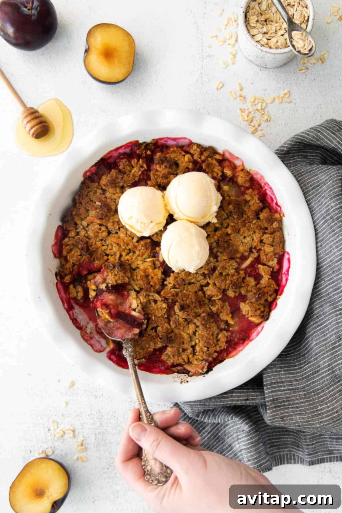 A perfectly baked plum crisp in a circular dish, showcasing its golden-brown topping and juicy plum filling.