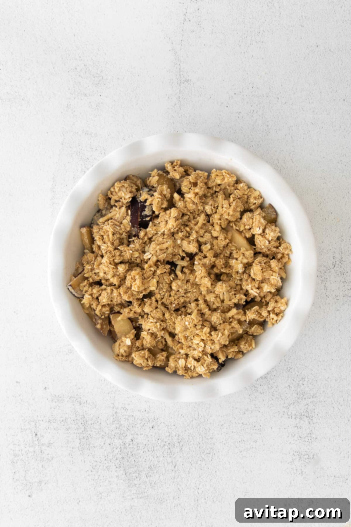 A freshly baked plum crisp in a glass baking dish, steam gently rising.