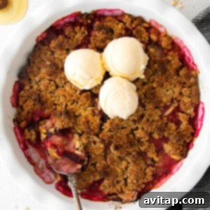 A warm plum crisp in a square baking dish, garnished with a sprig of mint.