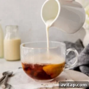 Effortless London Fog Delight 5 A person pouring milk into a cup of London Fog drink.