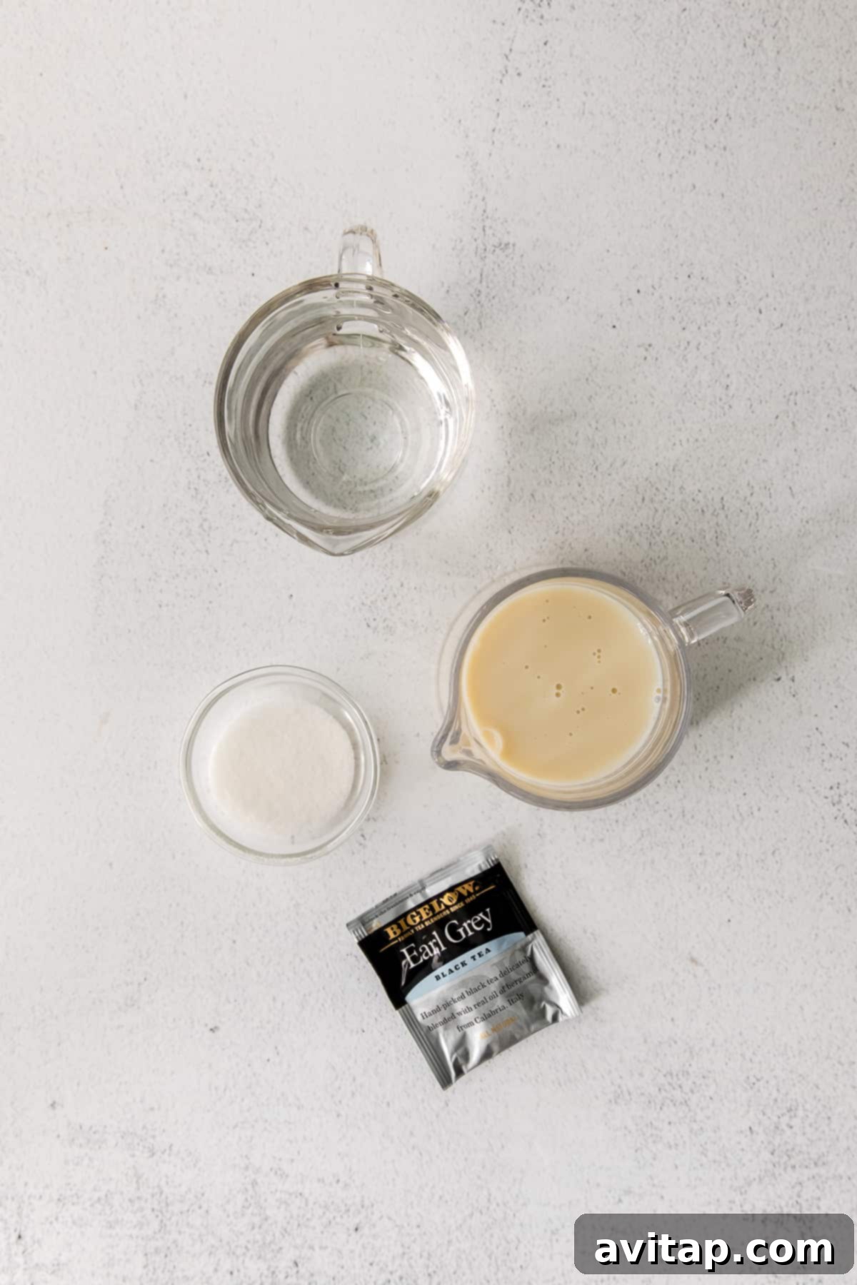Start your day with this deliciously easy London fog drink! This latte is made with earl grey tea, your favorite steamed milk and slightly sweetened. Simple ingredients for a London fog drink laid out in cups and mugs.