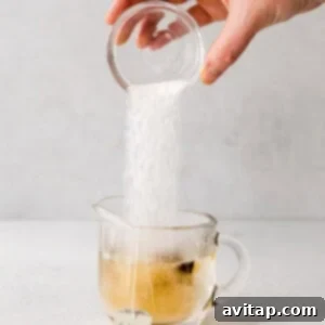 Effortless London Fog Delight 3 A hand is pouring sugar into a cup of London fog tea.