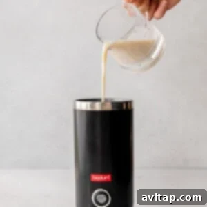 Effortless London Fog Delight 4 A person preparing a London Fog drink by pouring milk into a coffee maker.