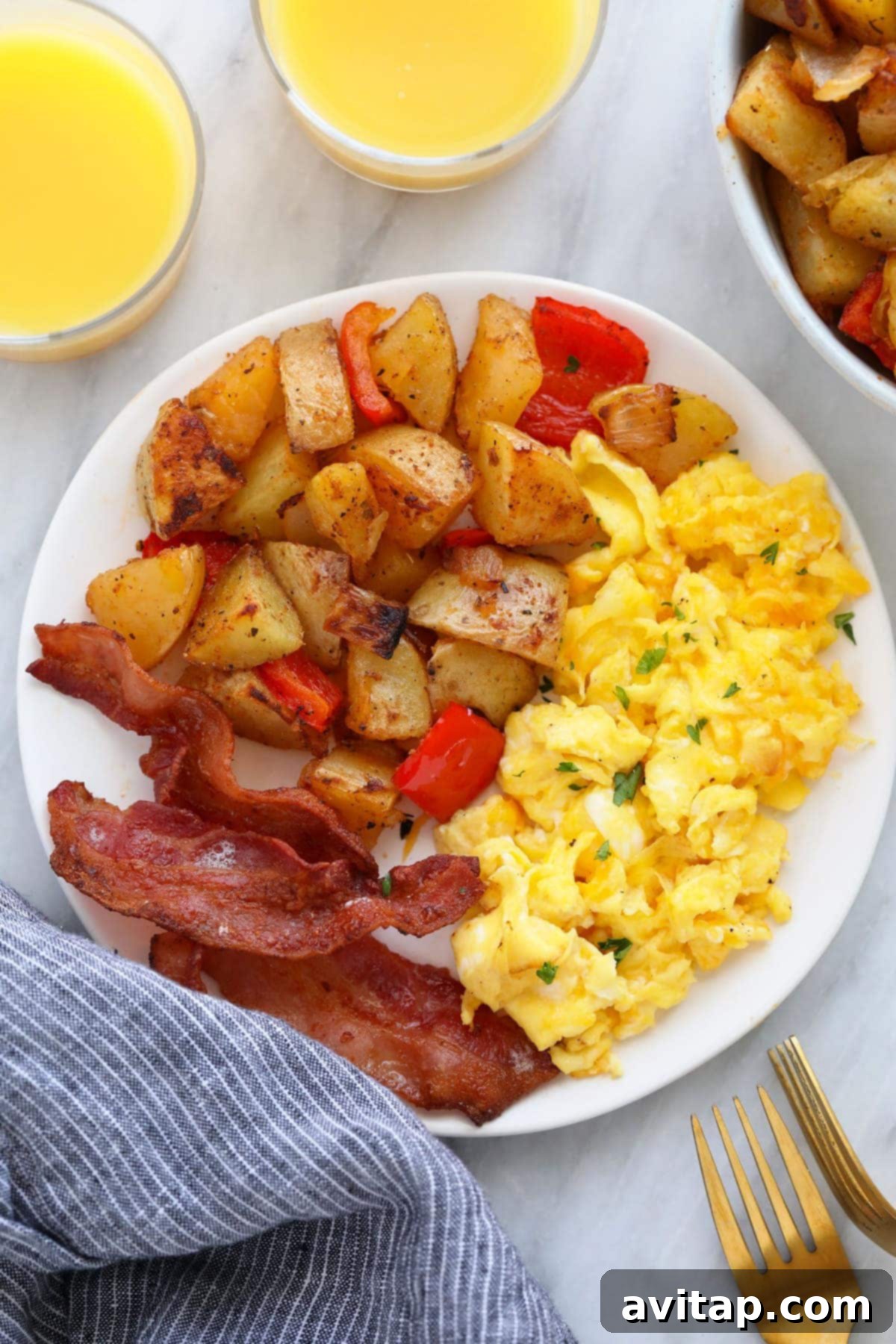 Crispy breakfast potatoes on a plate with eggs and bacon