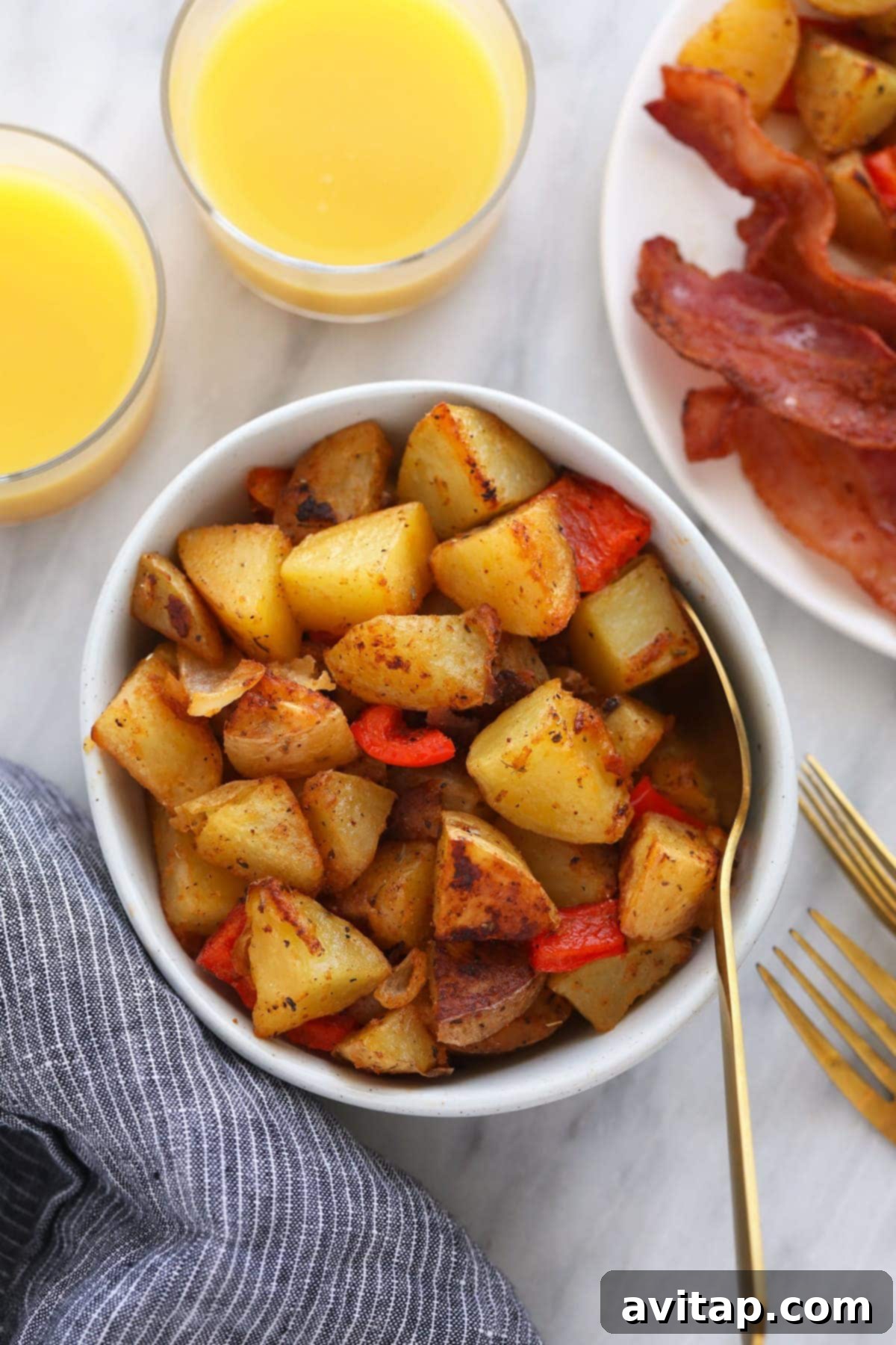 Breakfast potatoes in a bowl, served next to a glass of orange juice and coffee
