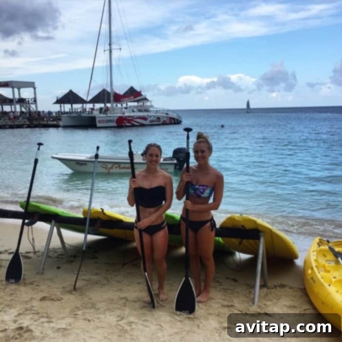 Two sisters enjoying stand-up paddleboarding (SUP) in the clear waters off Sandals Ochi Beach Resort in Jamaica, a fun activity on their Funjet Vacations trip.