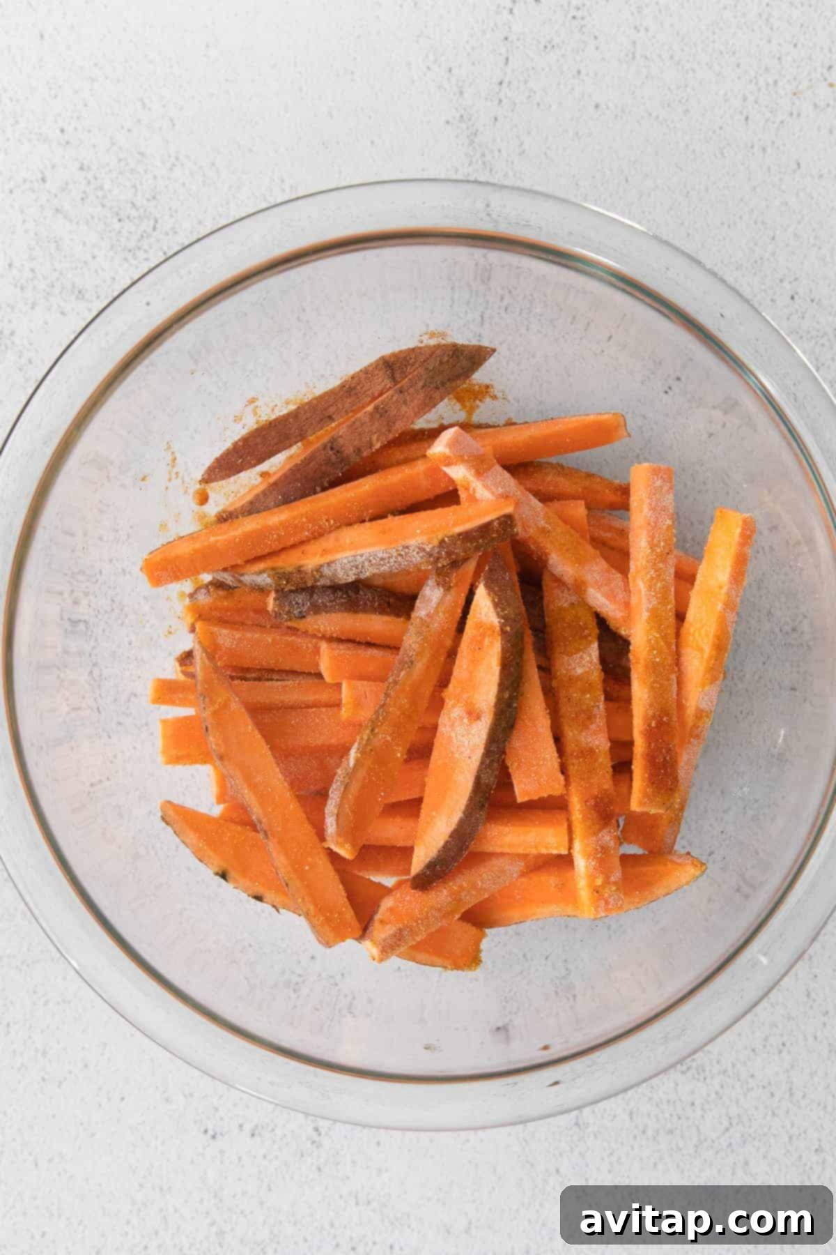 Air-Fried Sweet Potato Perfection 4 Sweet potato fries in a mixing bowl, generously tossed with olive oil and spices