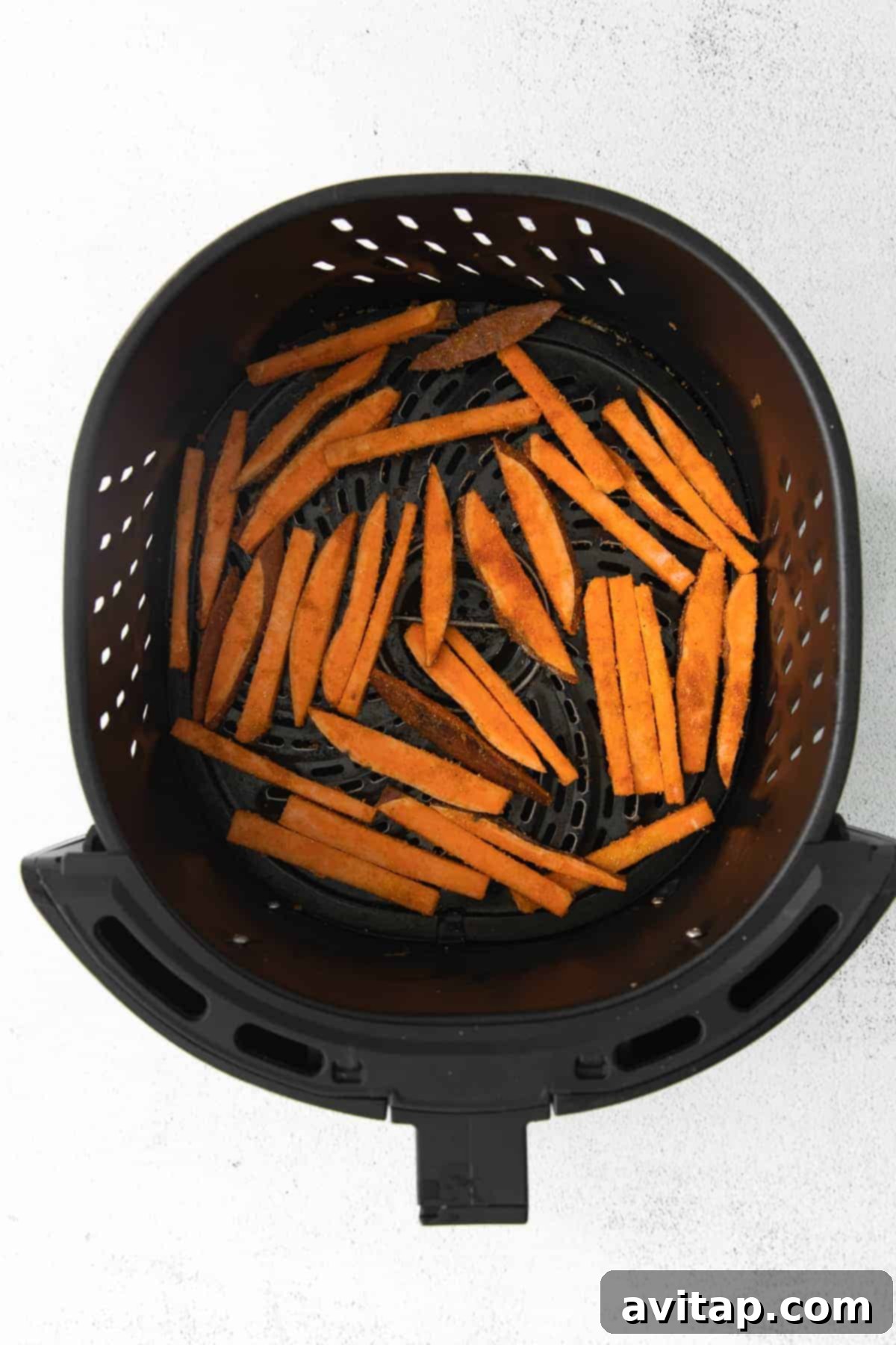 Air-Fried Sweet Potato Perfection 7 Golden brown sweet potato fries cooking in an air fryer basket, showing even crisping