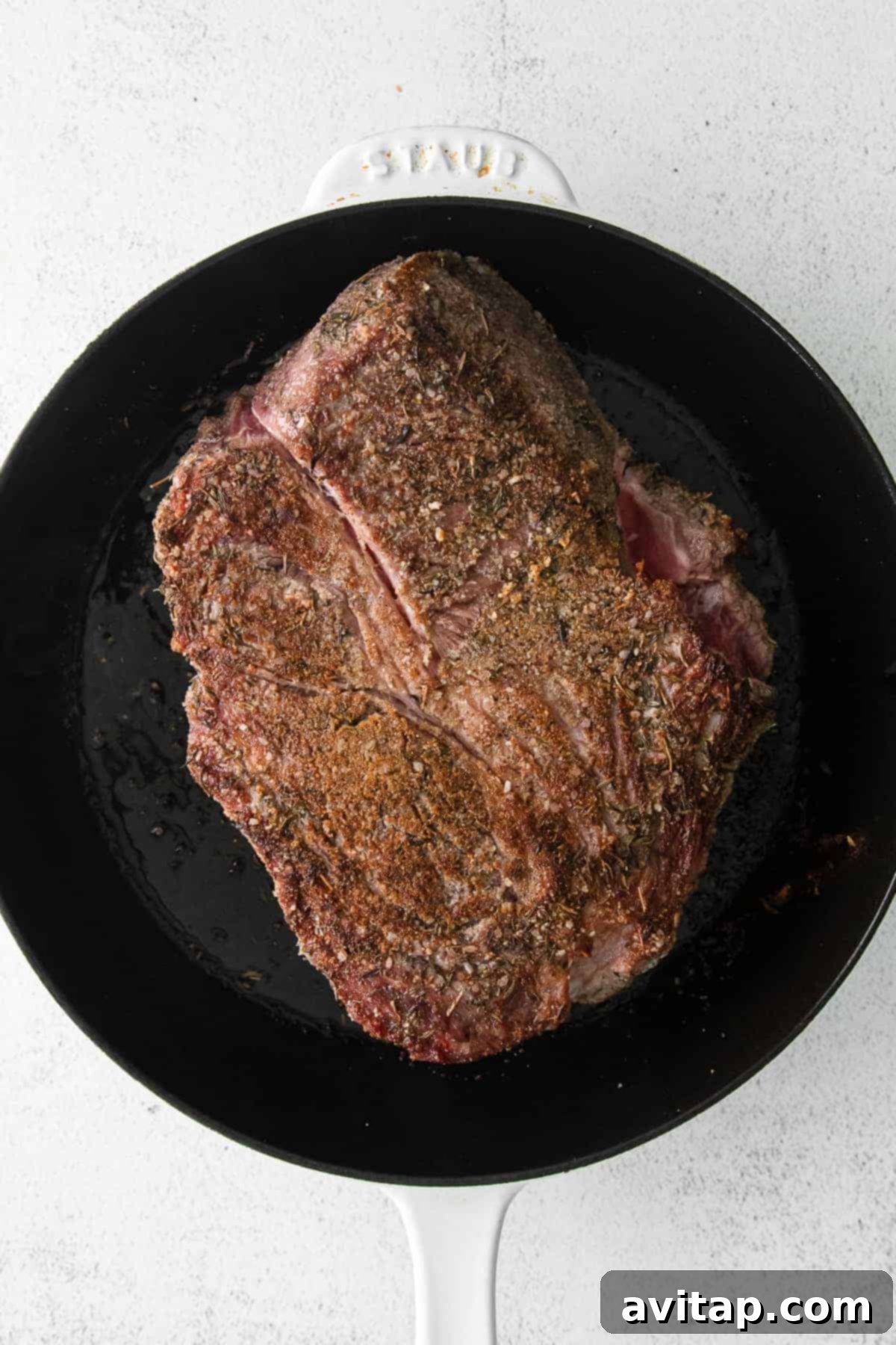 Chuck roast being seared in a hot cast iron skillet