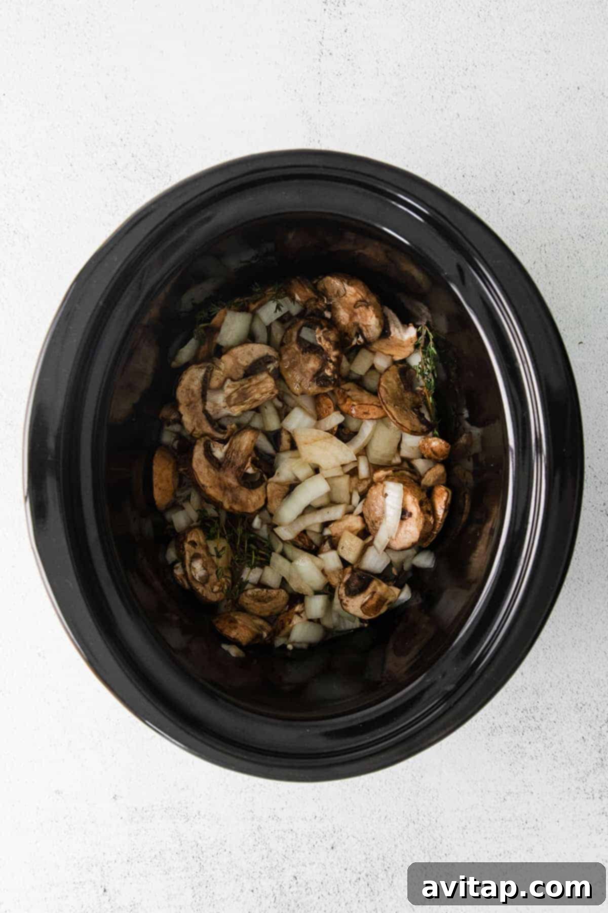 Vegetables and broth in a slow cooker, ready for beef