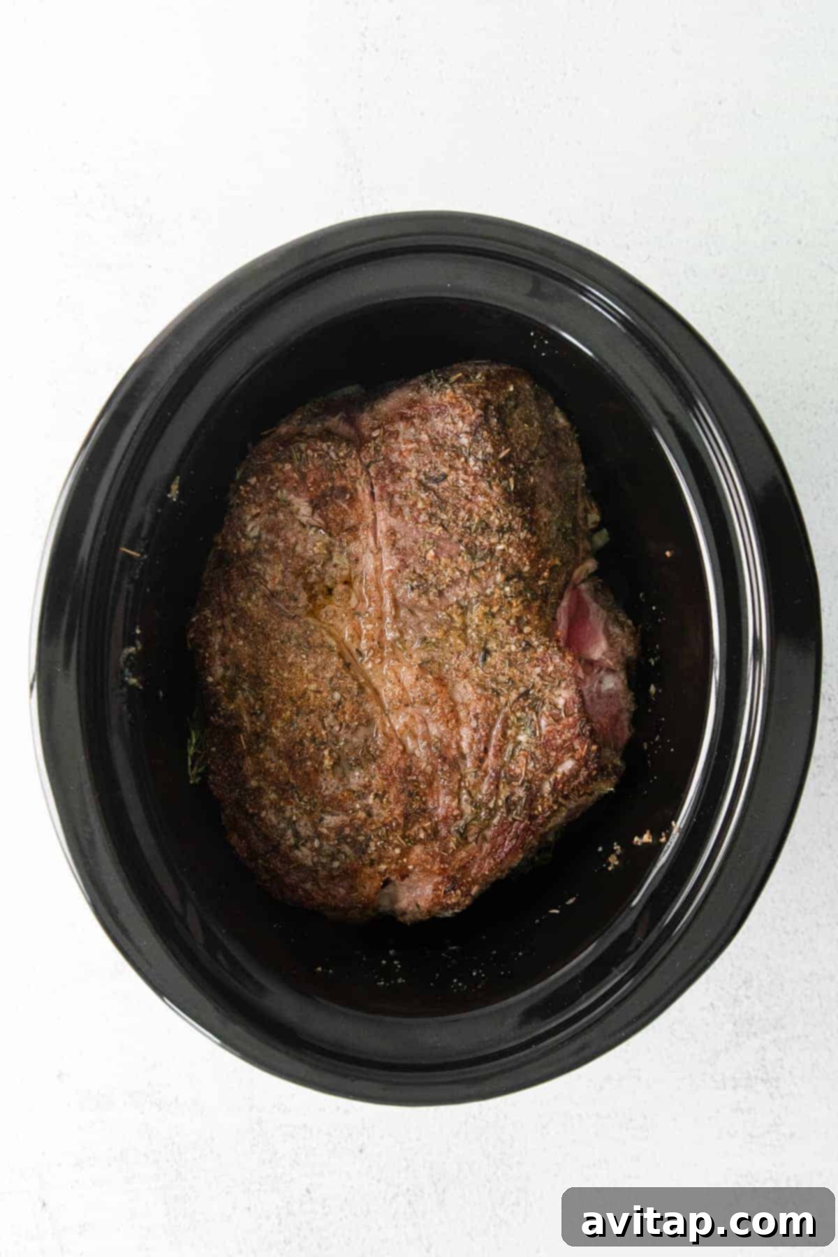 Tender chuck roast cooking in a slow cooker with vegetables