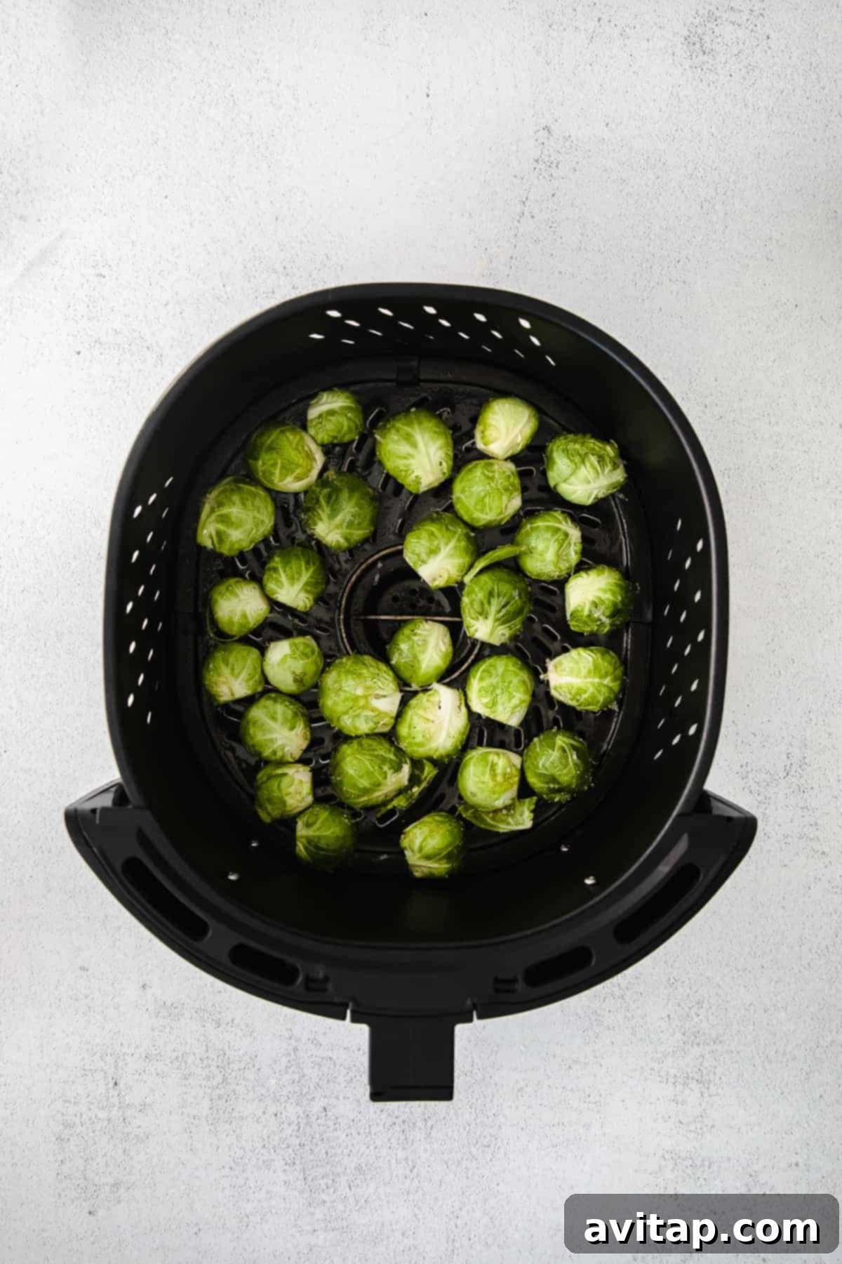 Halved Brussels sprouts perfectly arranged in an air fryer basket, ready for cooking.
