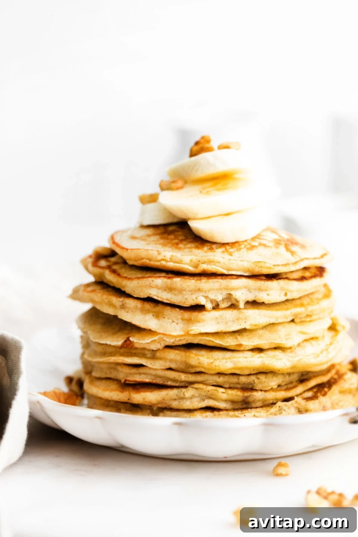 Perfectly Stacked Banana Pancakes A tall stack of fluffy banana pancakes topped with fresh banana slices, a drizzle of maple syrup, and a sprinkle of powdered sugar