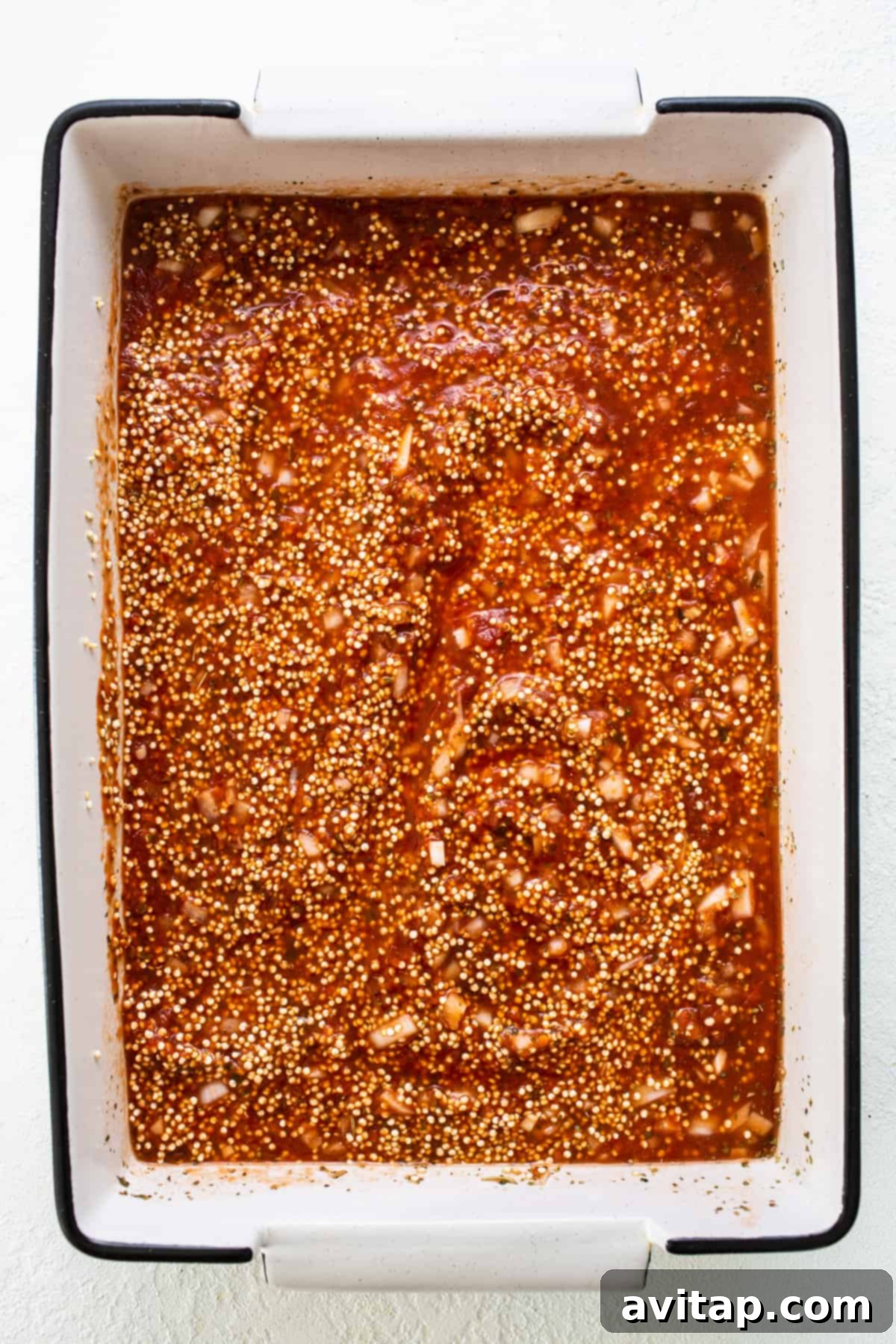 Easy Pizza Quinoa Bake 4 A baking dish filled with marinara sauce, quinoa, and spices, ready for baking.