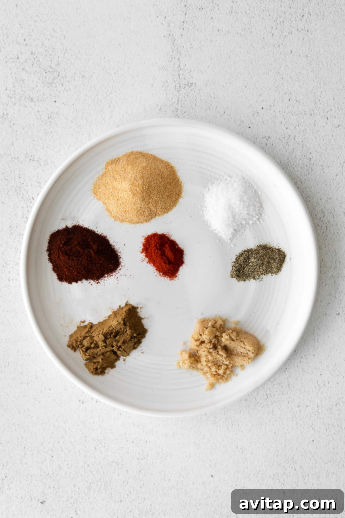The seven individual ingredients for steak taco seasoning neatly arranged on a plate, ready to be combined.