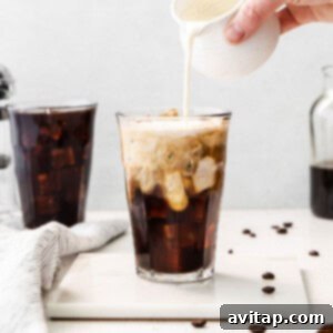 A glass filled with rich cold brew coffee, topped with a swirl of light cream, creating a beautiful layered effect.