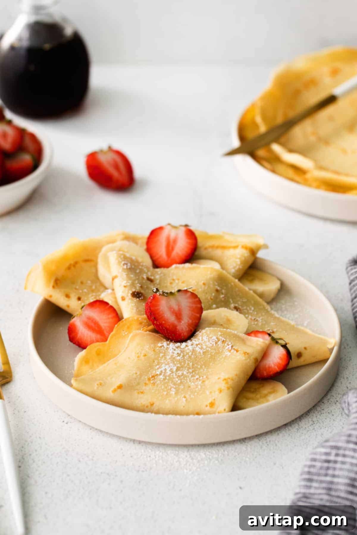 A neatly stacked pile of freshly made, thin crepes, showcasing their inviting golden color and delicate edges.