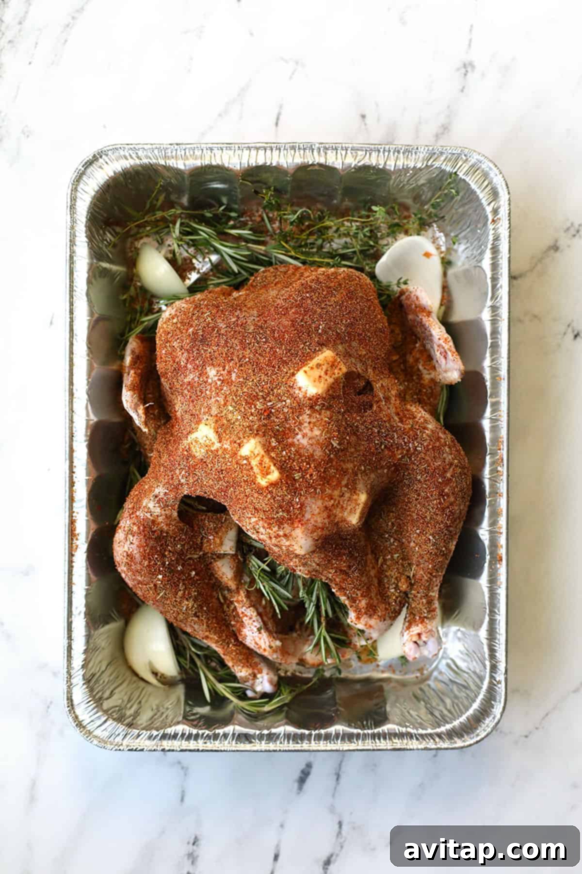 Smoked Turkey Perfection 4 A large turkey resting in a deep container, generously coated with dry rub seasoning, ready for smoking.