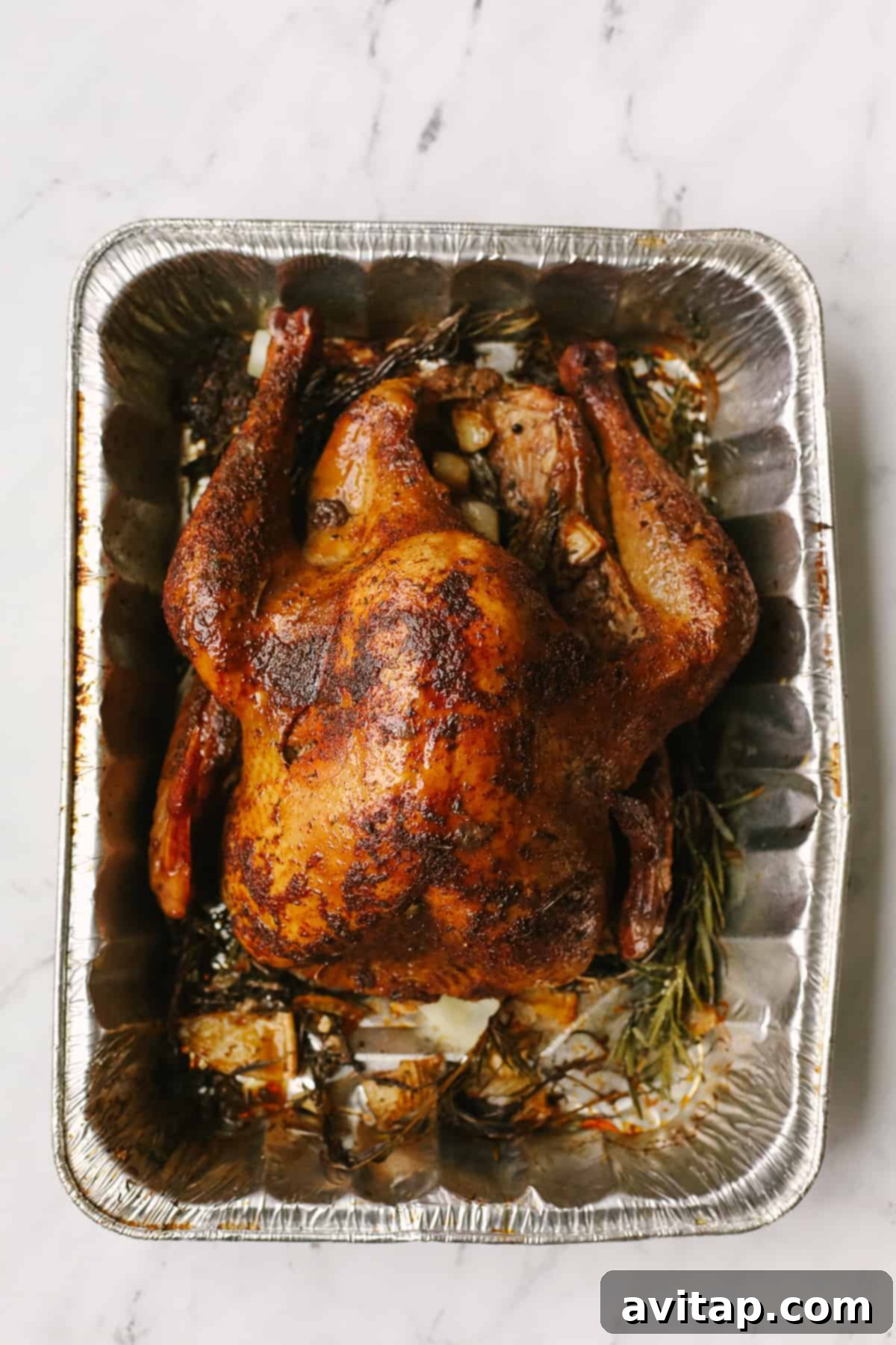 Smoked Turkey Perfection 7 A whole smoked turkey, beautifully browned, sits in an aluminum tray, ready to be carved.