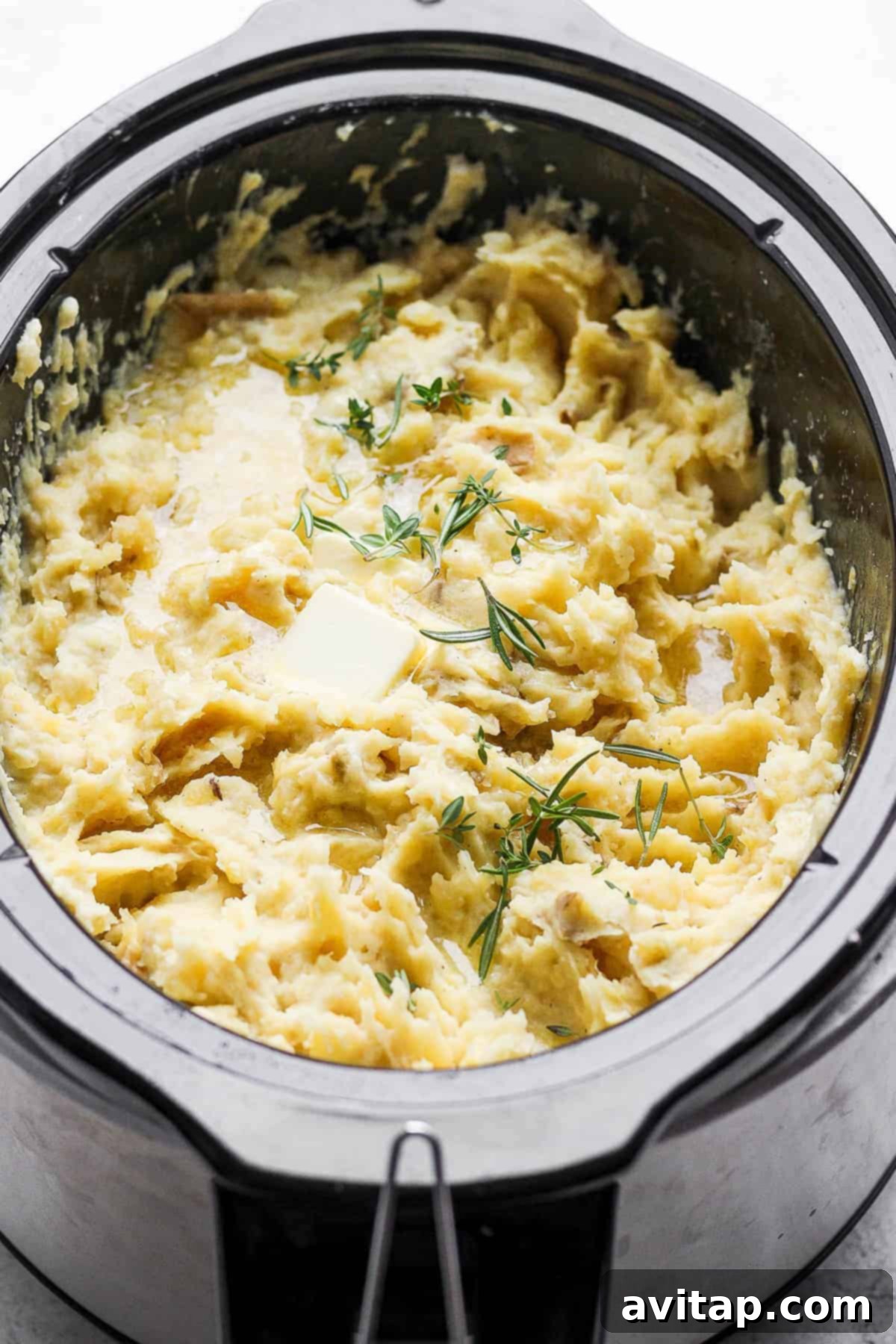 The Ultimate Crockpot Mashed Potatoes Recipe for Holidays and Gatherings Creamy crockpot mashed potatoes with a dollop of butter on top, served in a slow cooker