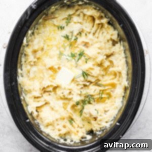A bowl of mashed potatoes in a slow cooker, garnished with fresh dill