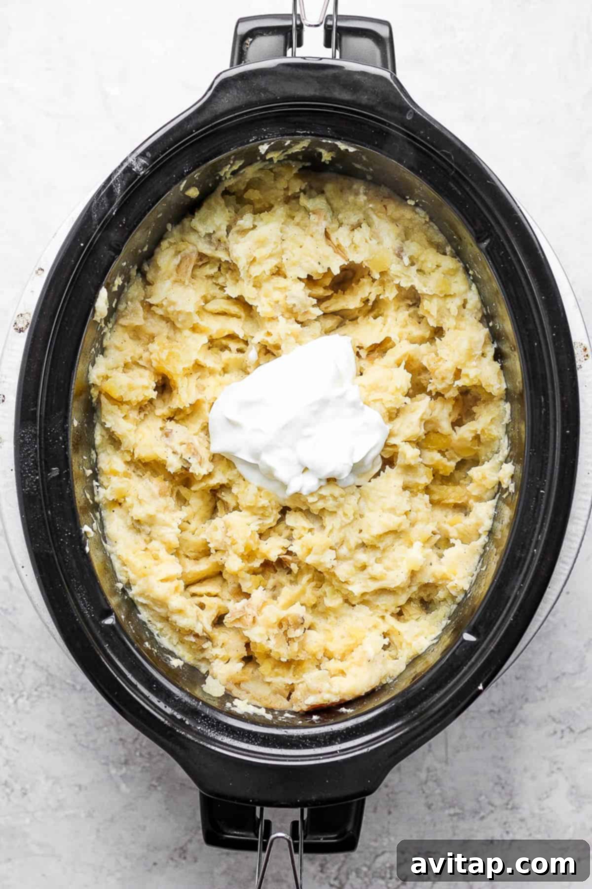 The Secret to Rich and Buttery Crockpot Mashed Potatoes Adding a generous pat of butter to freshly mashed potatoes in a slow cooker