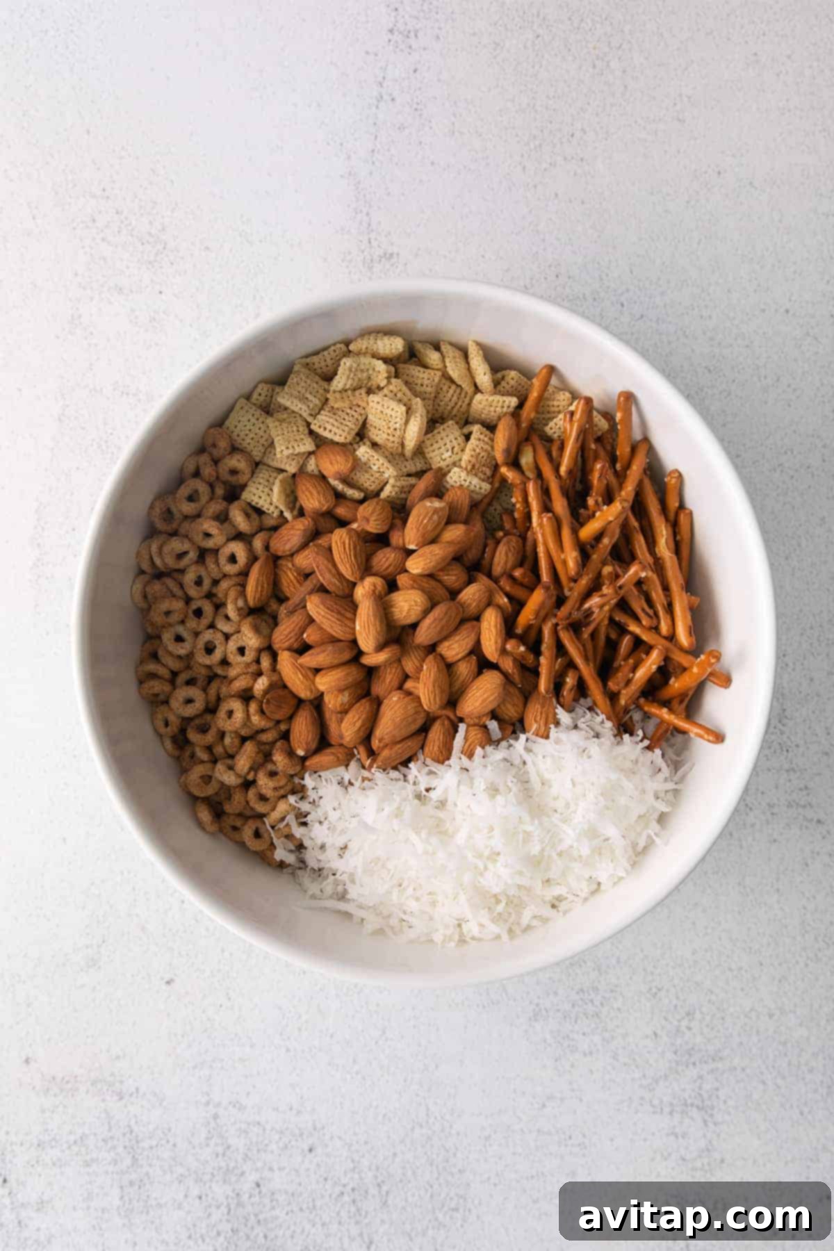 All the Chai Chex Mix ingredients beautifully combined in a large mixing bowl, ready for the next step of baking.