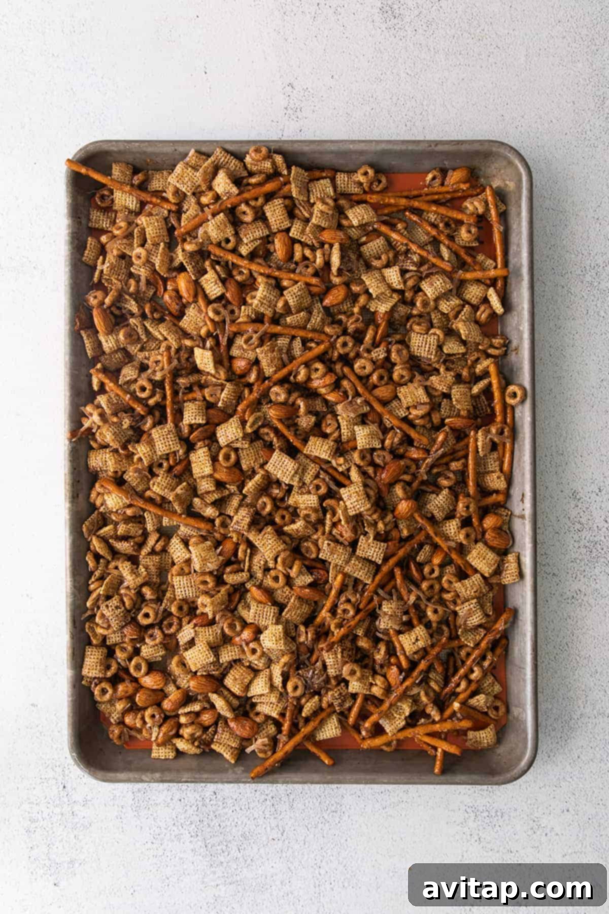 A freshly baked pan of Chai Chex Mix, glistening with maple chai syrup, showcasing its golden-brown perfection.