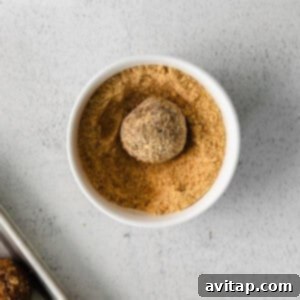 A pecan pie energy ball being rolled in graham cracker crumbs for a delicious coating.