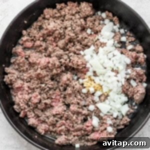 Ground beef and onions cooked in a skillet with flavorful slow cooker chili spices.