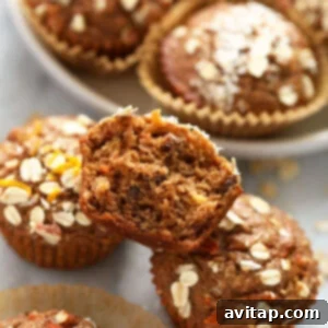 Glorious Morning Baked Oatmeal 2 Morning Glory Muffins, golden brown and studded with carrots and raisins, arranged enticingly on a kitchen counter.