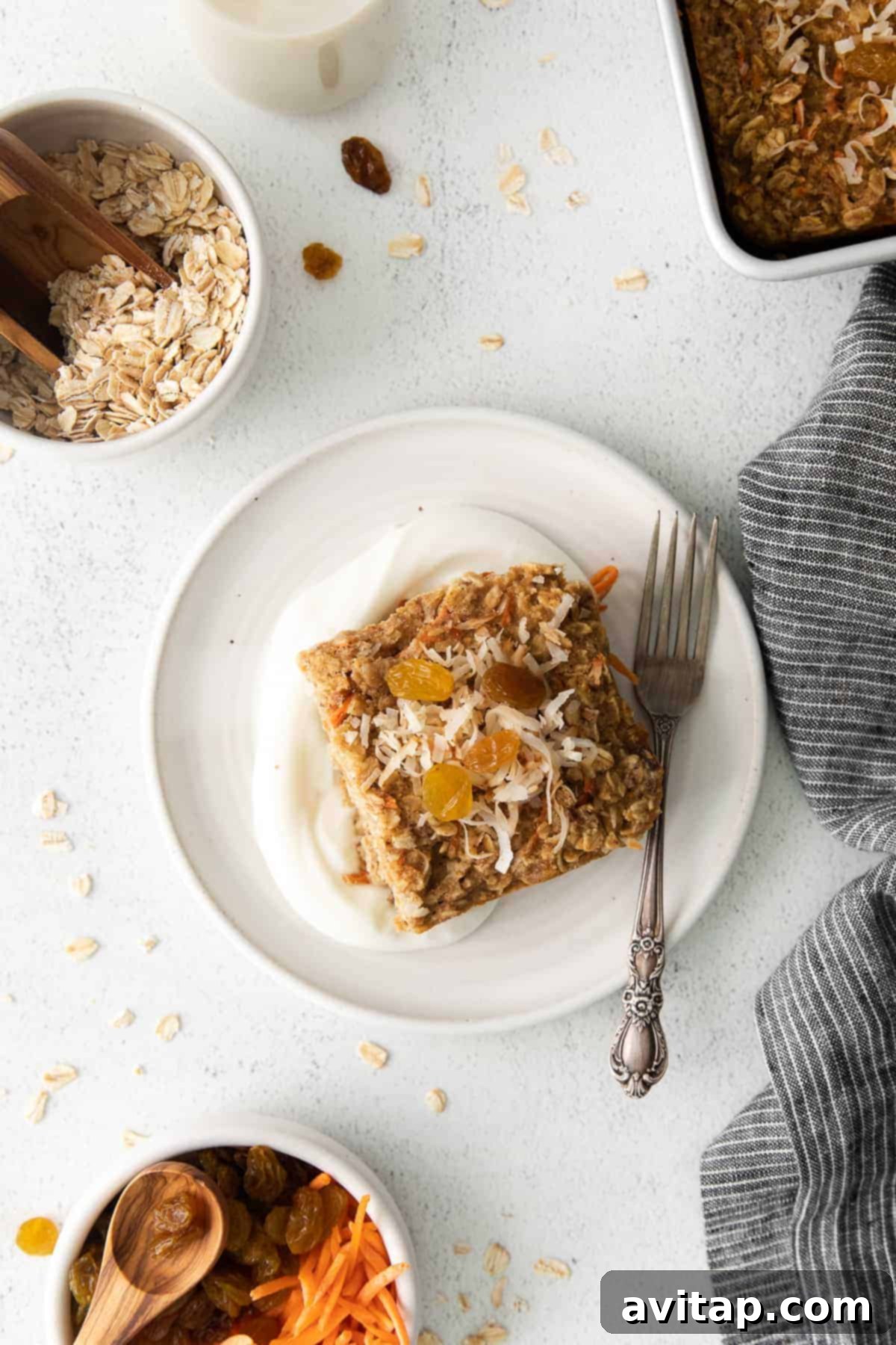 Served Morning Glory Baked Oatmeal A perfectly portioned slice of Morning Glory Baked Oatmeal, adorned with flaked coconut, resting on a white plate with a fork, invitingly ready to be eaten.