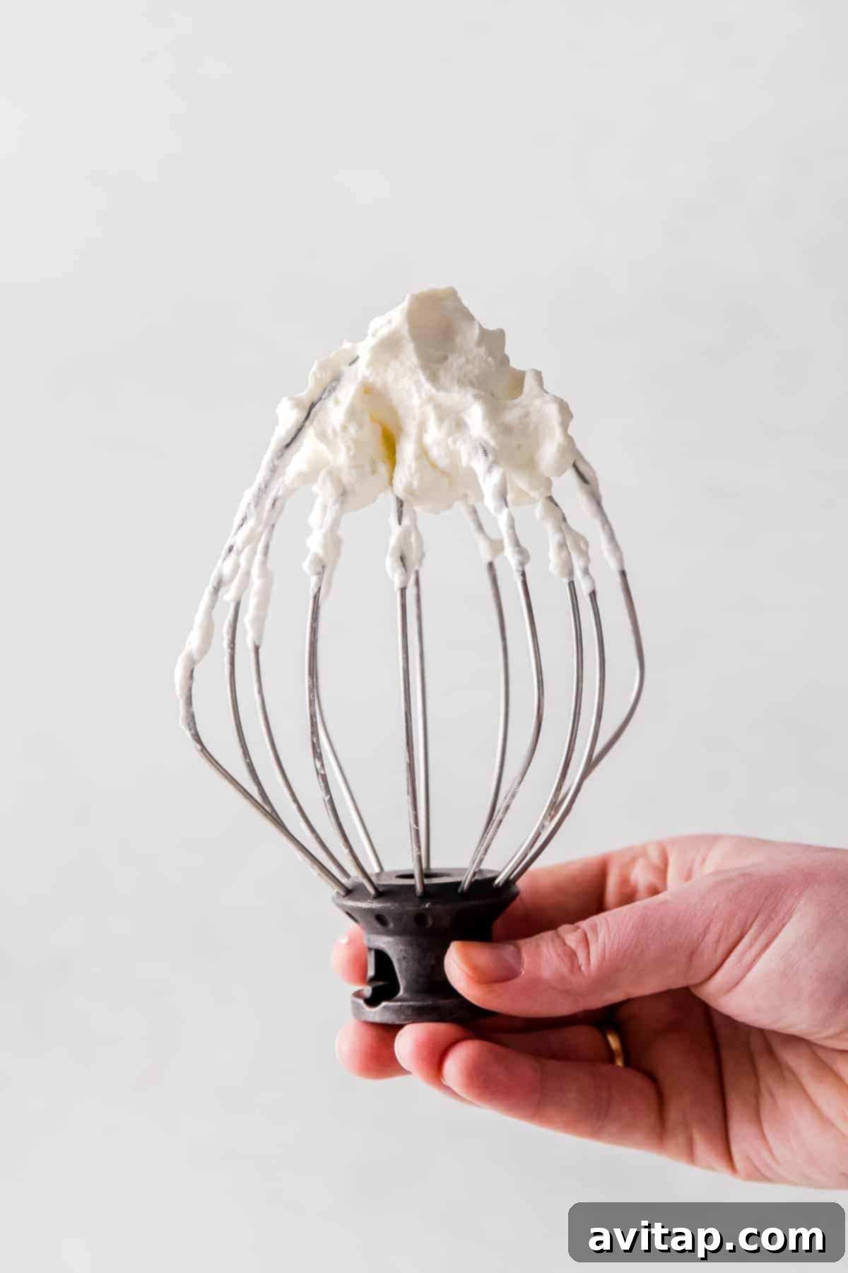 Perfect Homemade Whipped Cream 5 Perfectly whipped cream clinging to a whisk attachment, showcasing its ideal, airy consistency.