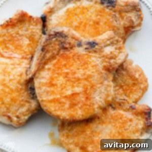 Two baked pork chops on a plate, garnished and ready to eat.