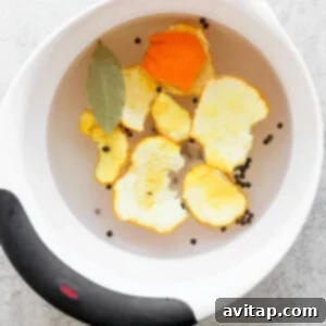 A bowl filled with a savory brine solution, featuring orange slices and peppercorns.