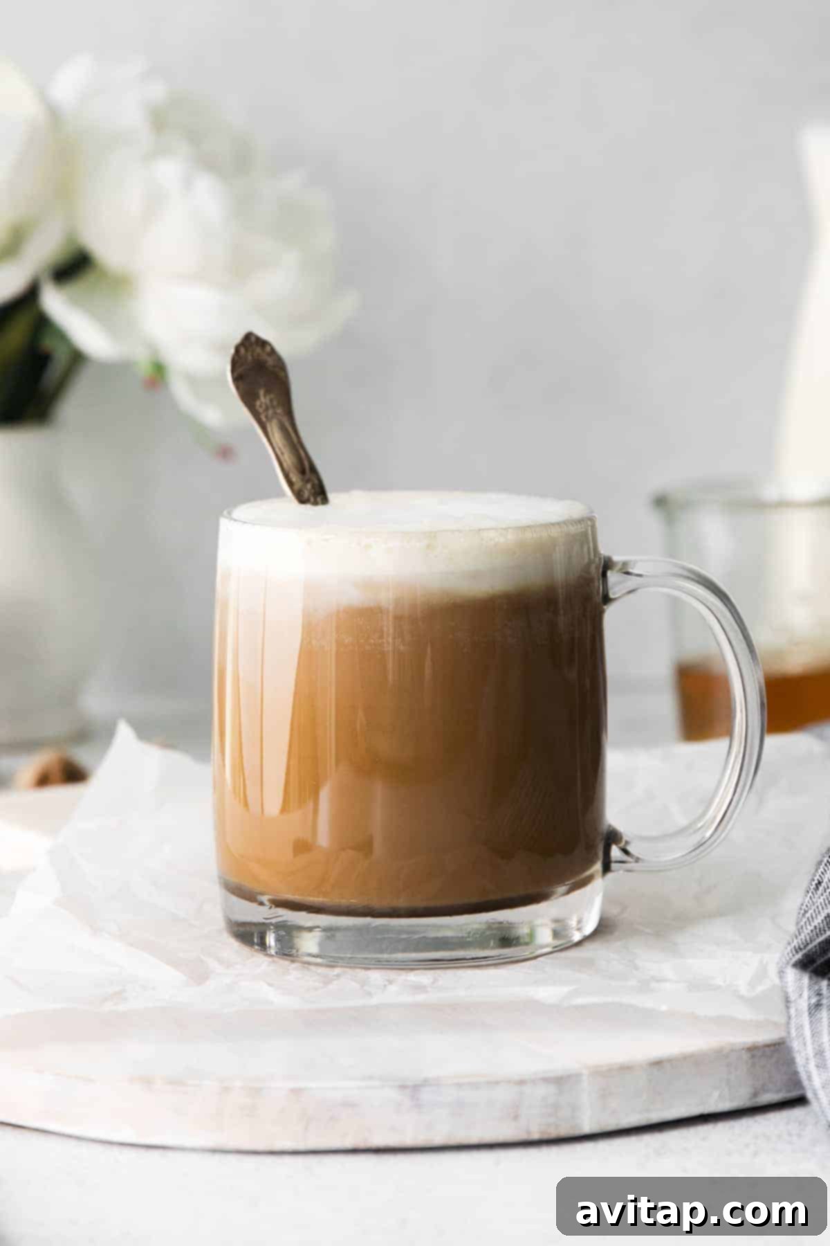 A beautifully frothed miel latte in a cozy coffee mug with a spoon, highlighting its creamy texture.