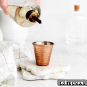 A shot glass filled with clear simple syrup, ready for use in cocktails and coffee.