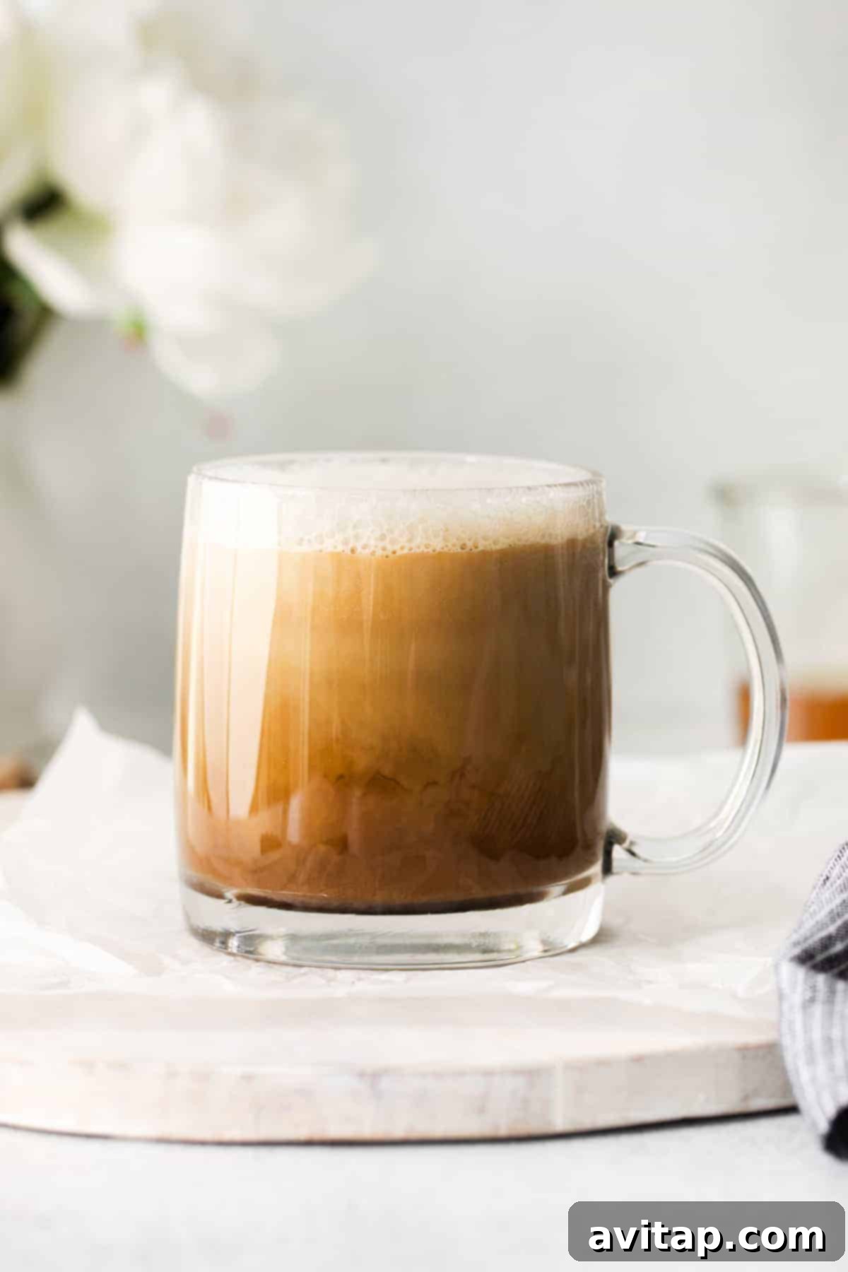 A delicious miel latte in a clear glass coffee mug, beautifully garnished with cinnamon and ready to be enjoyed.